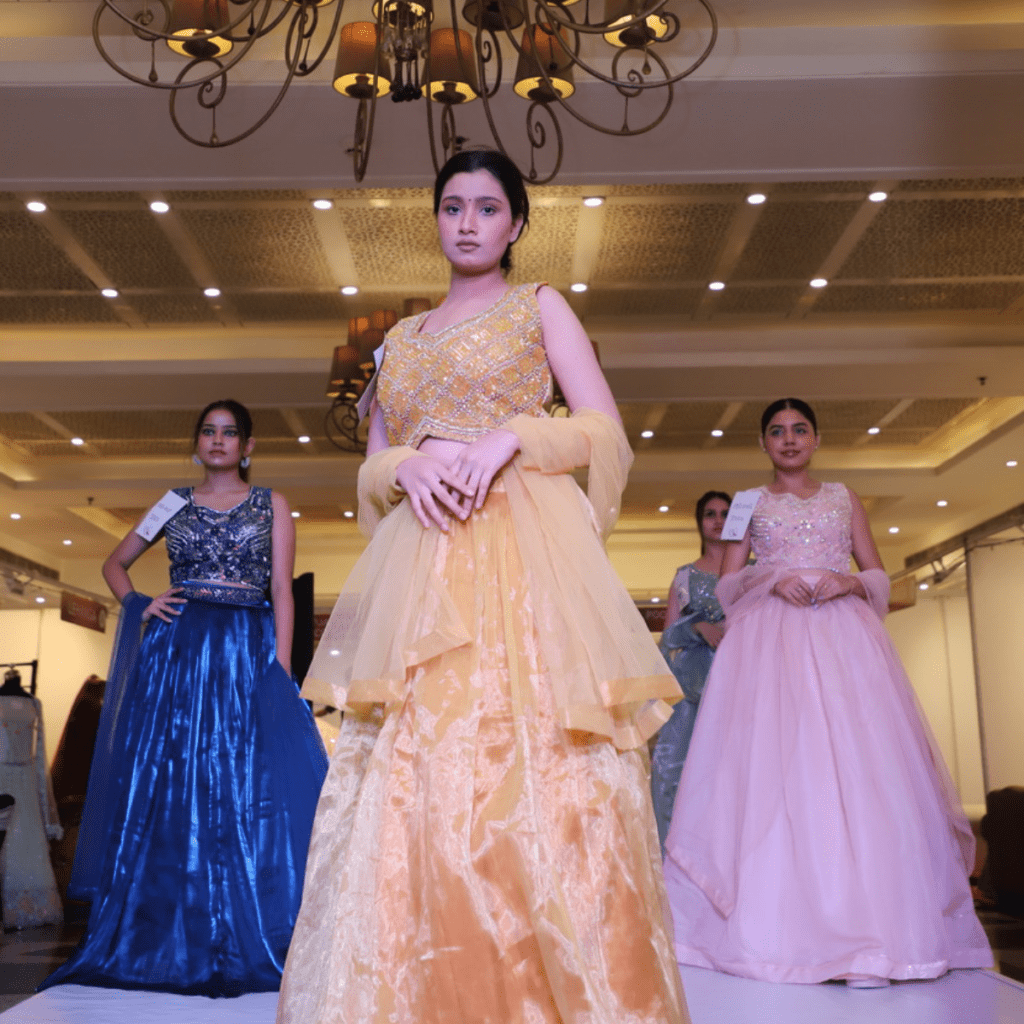 A girl displaying a orange saree design on stage.