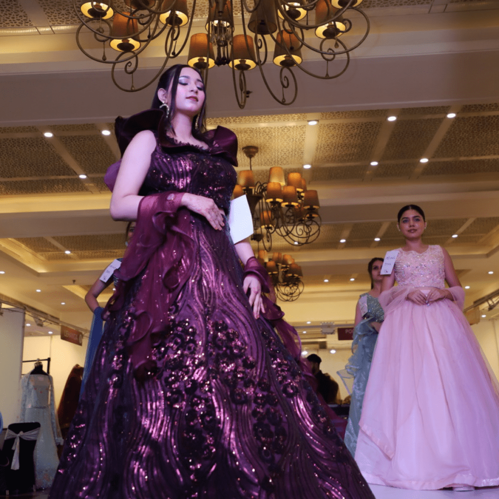 A girl displaying a wine gown design on stage.